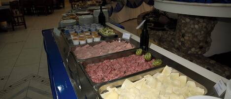 A buffet with various food options including meats, cheeses, and salads.