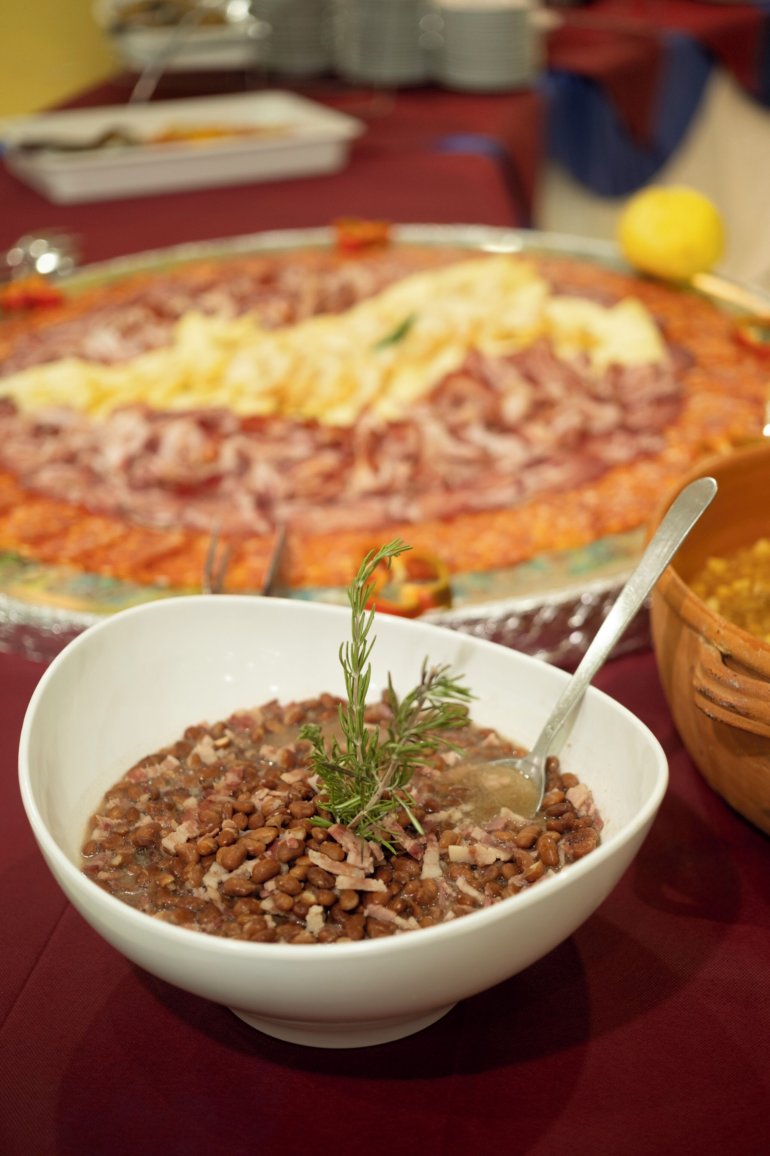 A dining table with a large pizza and a bowl of beans.