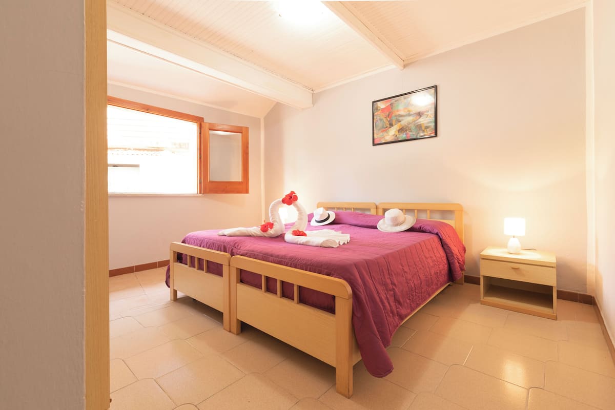 A bedroom with a bed, bedside table, and a window.