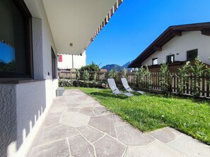 A patio with stone flooring, two lounge chairs, a wooden fence, and a mountain view in the background. - SiLENA Family Apartment (Lajen)
