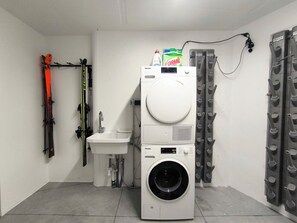 A compact laundry room with a washing machine, a sink, and a drying rack. - SiLENA Family Apartment (Lajen)