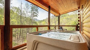 Ein Whirlpool auf einer Holzterrasse mit Blick auf einen bewaldeten Bereich.