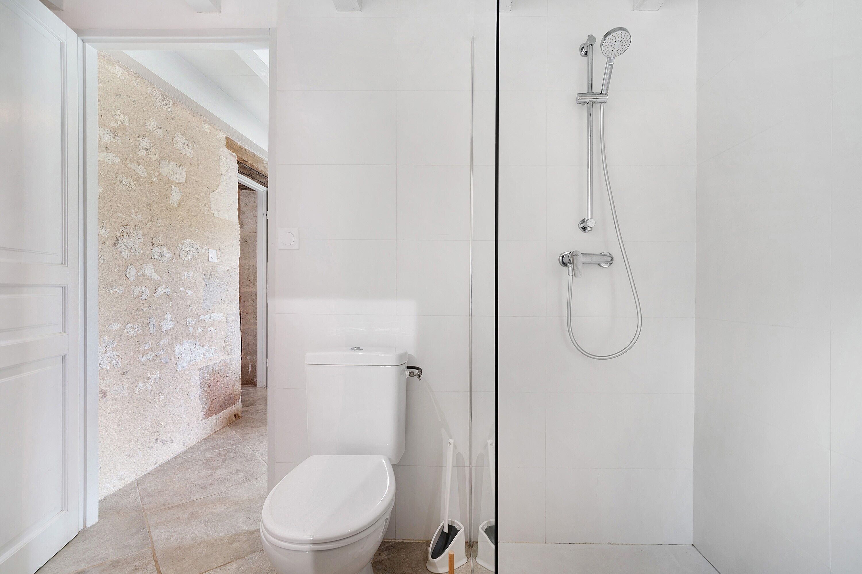 A bathroom with a toilet, shower, and a partially unfinished wall.
