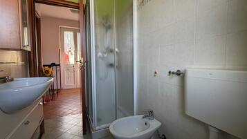 Un baño con ducha, lavamanos e inodoro.