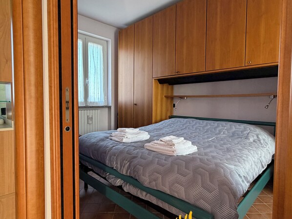Ein Schlafzimmer mit einem Bett, einem Holzschrank und einem Fenster mit Vorhängen.