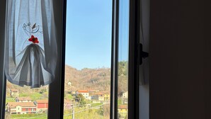 Une fenêtre donnant sur un village et des collines.