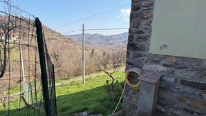 Un bâtiment en pierre offrant une vue sur un champ verdoyant et des montagnes.