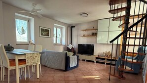 Un grand espace de vie comprenant une table à manger, des chaises, un canapé, un téléviseur et un escalier.