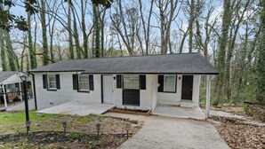 Ein eingeschossiges Haus mit einer Veranda, einem kleinen Vorgarten und einer Auffahrt zum Eingang.