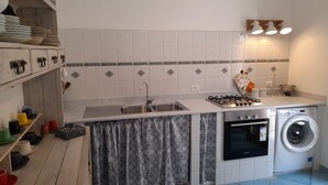 Cocina compacta con lavamanos, estufa y lavadora integrada.