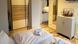 Ein Hotelzimmer mit zwei Betten, einem Fernseher, einem Schrank mit einem Bild von einem Hirsch und einem Holzboden.