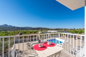 Un balcon avec une piscine, une table avec des chaises et une vue sur le paysage.