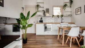 Una cocina moderna con armarios blancos, una mesa de comedor de madera y una planta en maceta.