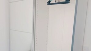 A walk-in closet with a mirrored closet door, a hanging rod, and a small bench.