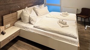 Un dormitorio moderno con una cama grande, paneles de madera en la pared, un ventanal y una silla.