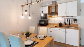 Et moderne køkken med hvide skabe, en mikrobølgeovn og en hængende lampe.