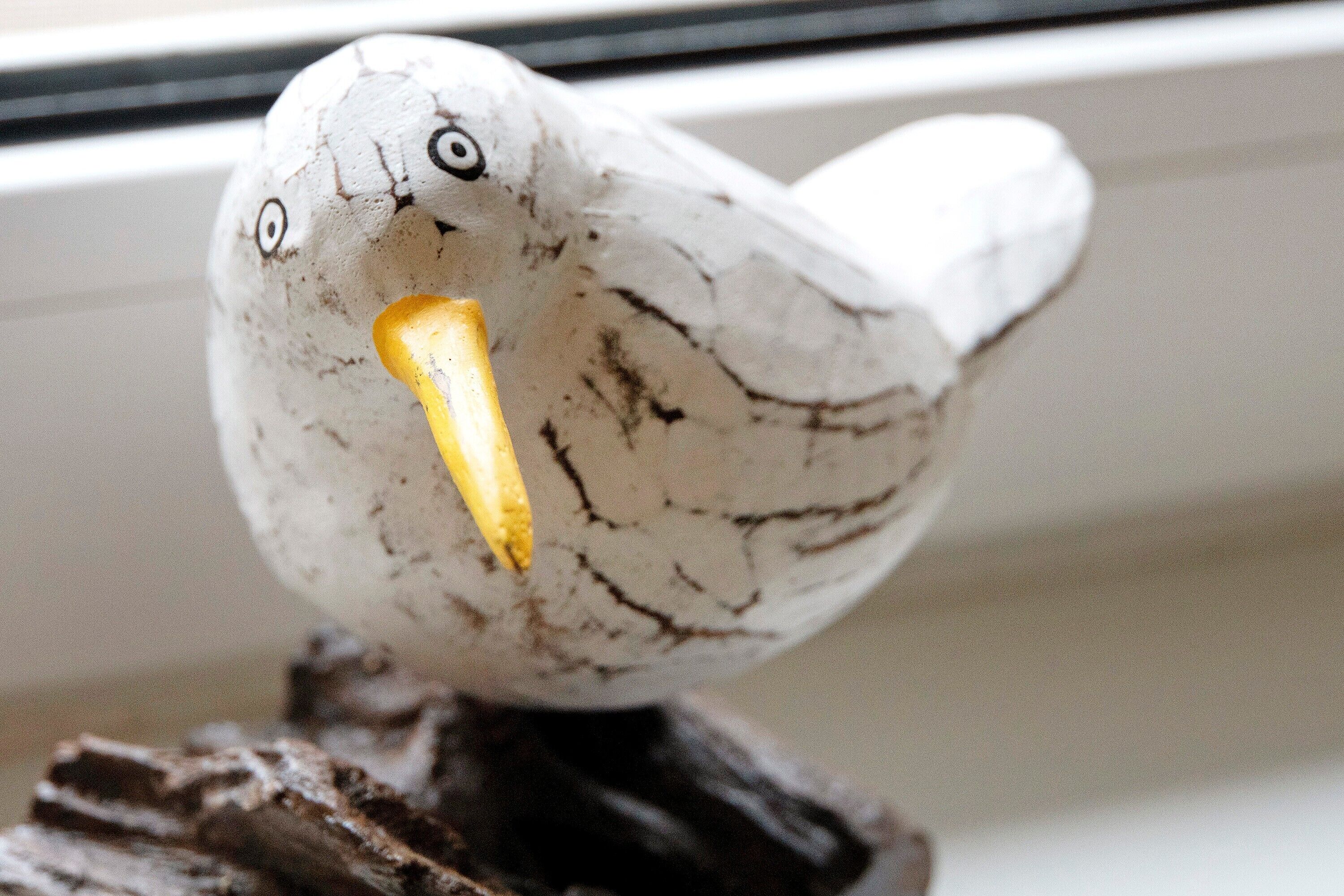 Eine vogelähnliche Dekoration auf einem dunklen Holzfuß.