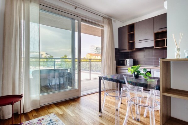 Una cocina moderna con gabinetes oscuros, una mesa de vidrio y sillas transparentes.