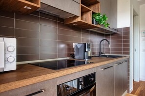 Una cocina moderna con horno empotrado, cafetera y pileta.