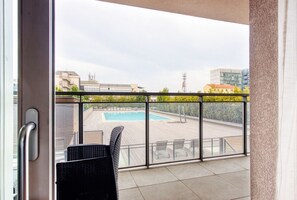 Un balcón con vistas a una piscina, sillas y barandilla.