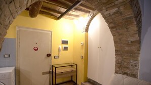A bathroom with a tiled floor, a white door, a glass table, and a brick wall. - Cozy suite in the heart of Perugia, perfect for 2 guests.Elegant room, comfortable living room and kitchen equipped to feel right at home.The unique detail? The natural stone walls, which give charm and character to the environment.Bright and well-kept,  (Perugia)