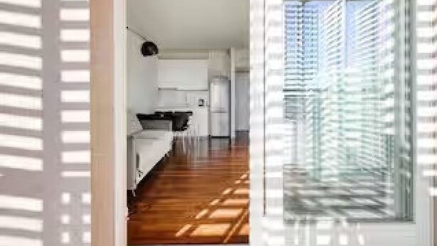 Een moderne keuken met witte kasten, een zwart aanrecht en een houten vloer.
