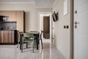Una cocina moderna con comedor, televisor montado en la pared y una puerta con cerradura.