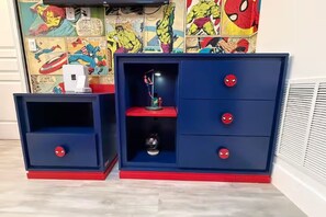 Zwei blaue und rote Stauraume mit Schubladen und Regalen vor einer Wand mit Comic-Kunst.