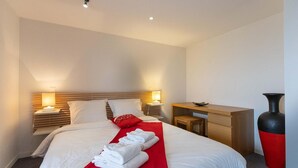 Een hotelkamer met een bed, nachtkastjes, een bureau en een grote vaas.