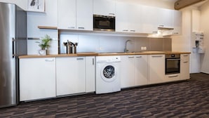 Een moderne keuken met witte kasten, een roestvrijstalen koelkast, een inbouwoven, een vaatwasser en een wasmachine.