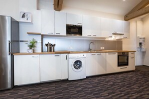 A modern kitchen with white cabinetry, a stainless steel refrigerator, a built-in oven, a dishwasher, and a washing machine. - Chalet in Paradiski With Spa & Valley Views (Peisey-Nancroix)
