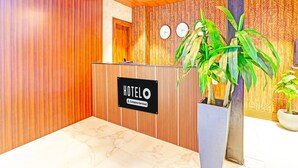 A hotel reception area with a wooden interior, a reception desk, and two clocks on the wall. - Super Hotel O Raipur (Raipur)