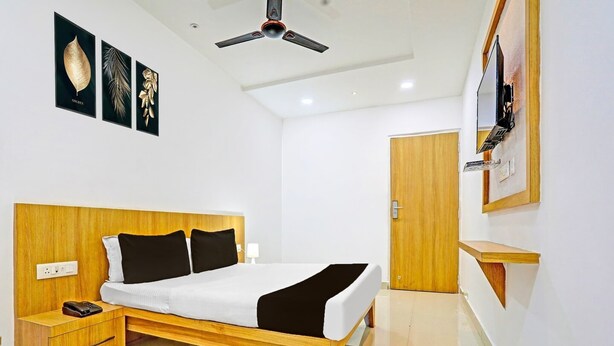 A modern hotel room with a wooden bed, bedside table, and a ceiling fan. - Super Hotel O Raipur (Raipur)