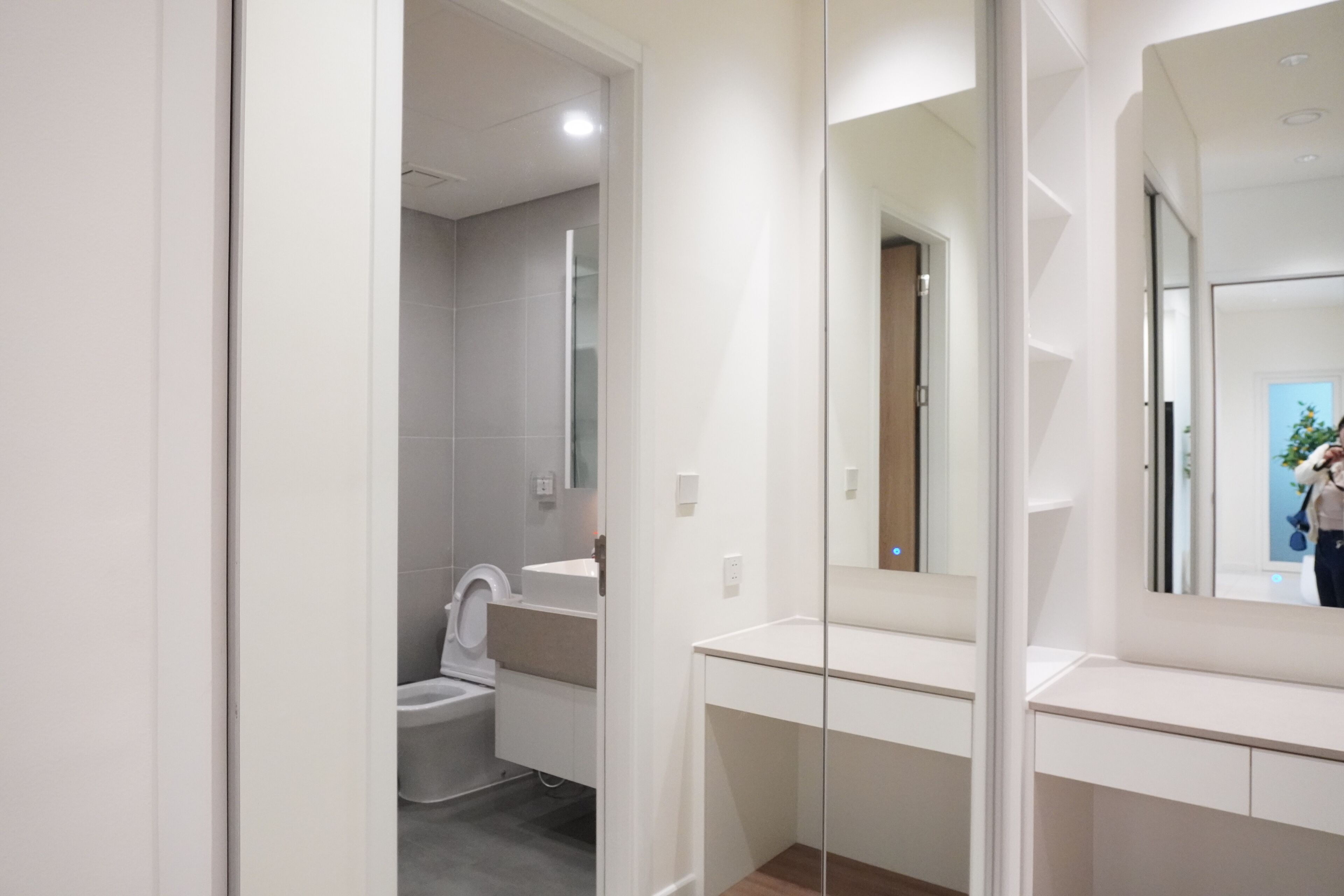 A modern bathroom with a toilet, sink, and mirror.