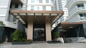 Un edificio moderno con una entrada curva, una señal de 'No Entry' y una persona caminando al frente.