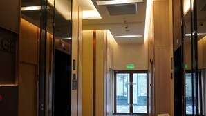 Un vestíbulo de hotel con piso de mármol, paneles de madera y un ascensor.
