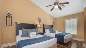 Ein Schlafzimmer mit zwei Betten, einem Deckenventilator und Holzböden.