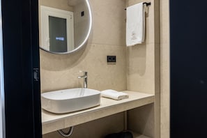 Casa de banho moderna com um espelho redondo, uma pia branca e um porta-toalhas.