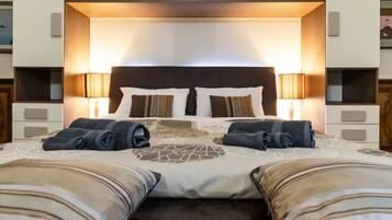 Una camera d'albergo con un letto grande, due abat-jour e un poggiatesta illuminato.
