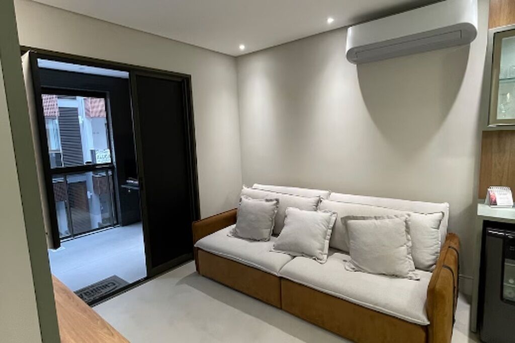 A modern living room with a sofa, a sliding door, and a small kitchenette area.