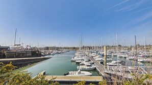 En lysthavn med mange både i havnen, klart skys og et vandvejsstræk.