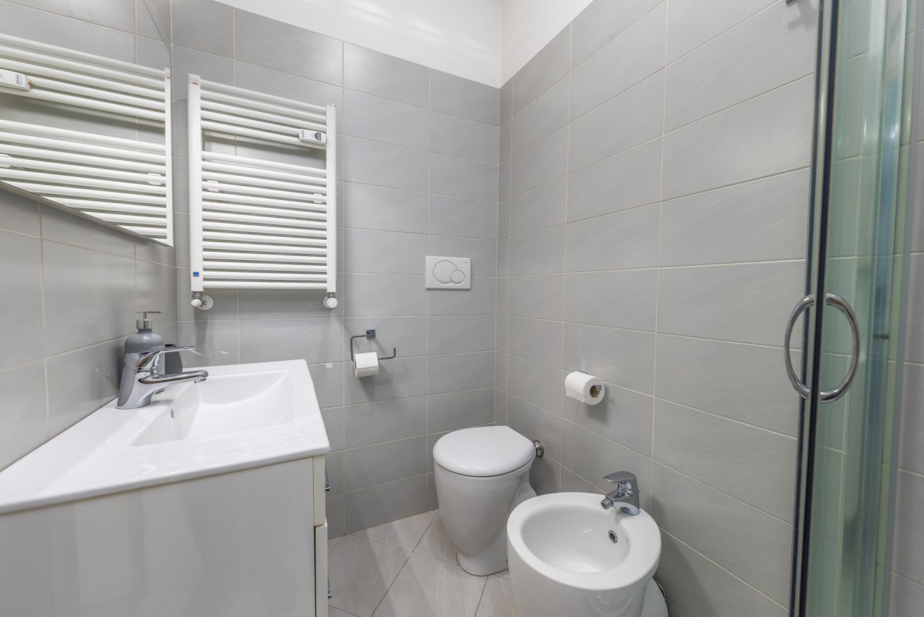 Une salle de bain avec un lavabo blanc, des toilettes, un bidet et une douche à parois de verre.