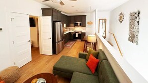 A modern kitchen with dark cabinets, a stainless steel refrigerator, and a dining area with a table and chairs.