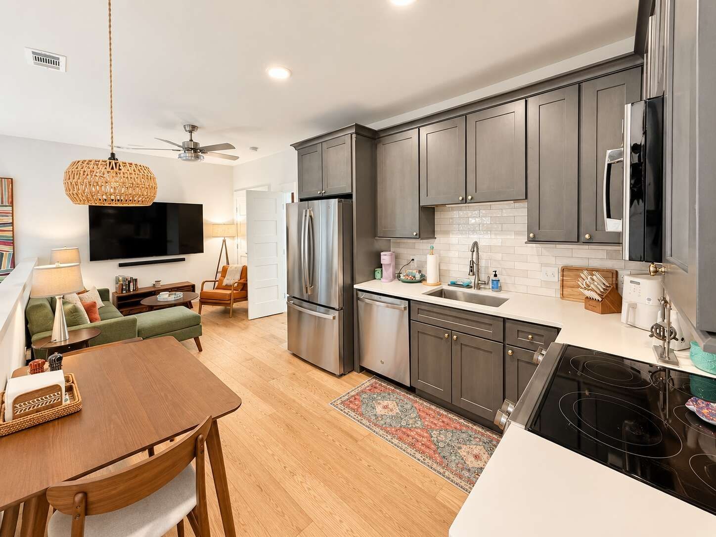 A modern kitchen with grey cabinets, a stainless steel refrigerator, and a built-in dishwasher.