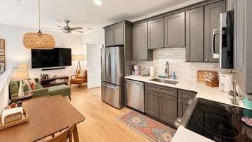 A modern kitchen with grey cabinets, a stainless steel refrigerator, and a built-in dishwasher.