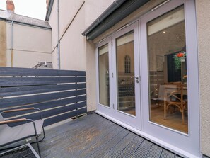 Eine Terrasse mit Sitzbank, eine Glastür zum Innenbereich und ein kleiner Tisch mit Stühlen.