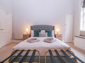 A neatly arranged bedroom with a bed, bedside tables, and a window. - Stylish Town Apartment (Ross-on-Wye)
