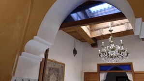 Un arco de entrada que conduce a una habitación con una araña, vigas de madera y un tapiz decorado.