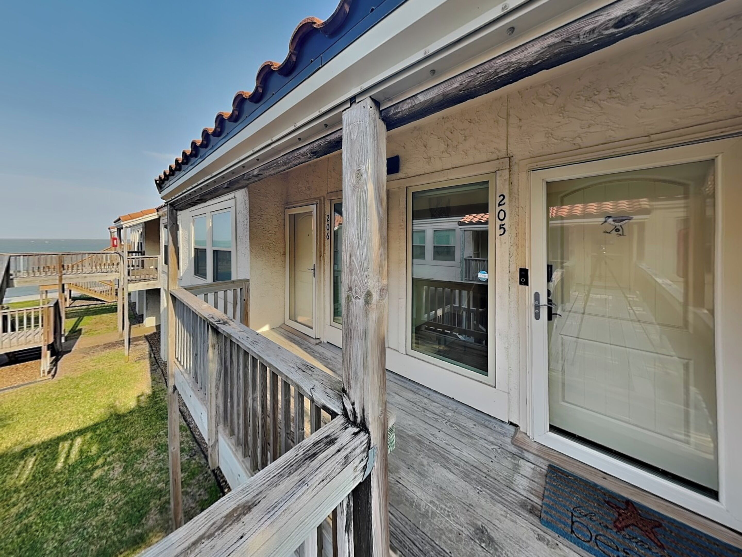 A beachfront property with a wooden deck, a balcony, and a view of the ocean.