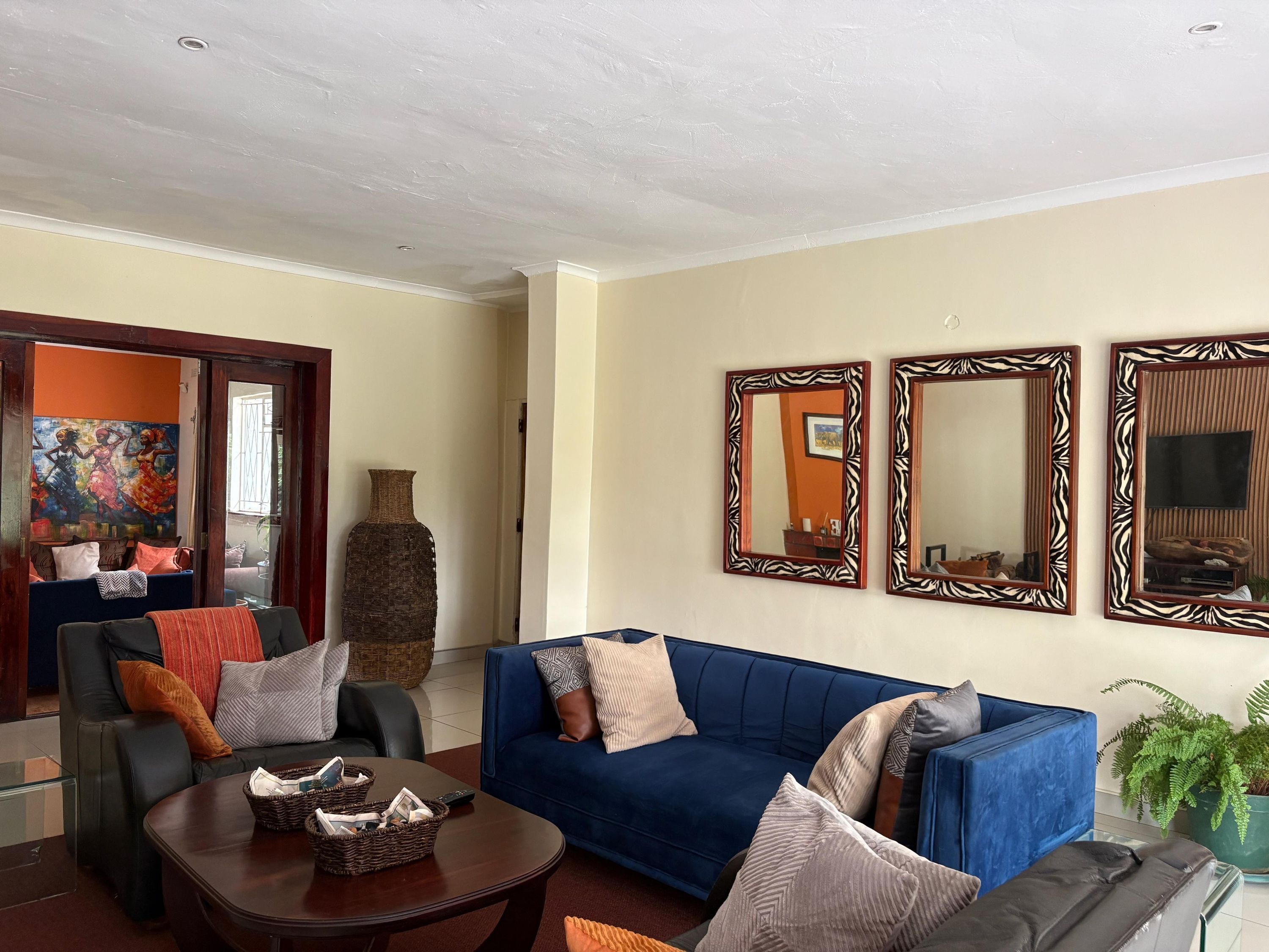 A living room with a blue sofa, a coffee table, and three wall-mounted mirrors.
